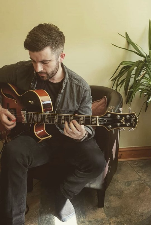 James Davies playing a hollow-body guitar